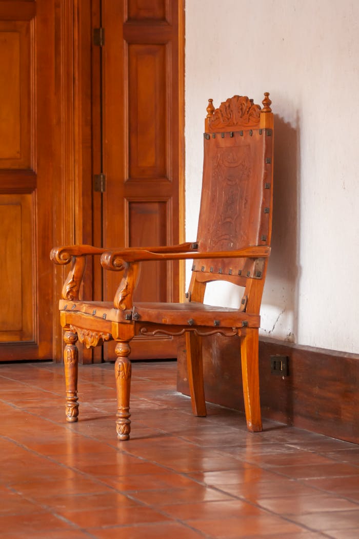 Classic wooden chair with intricate carvings in a rustic indoor setting.
