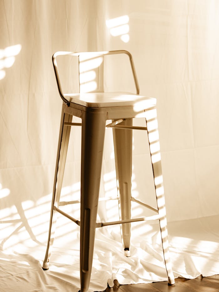 A white high chair illuminated by soft natural light, casting shadows indoors.