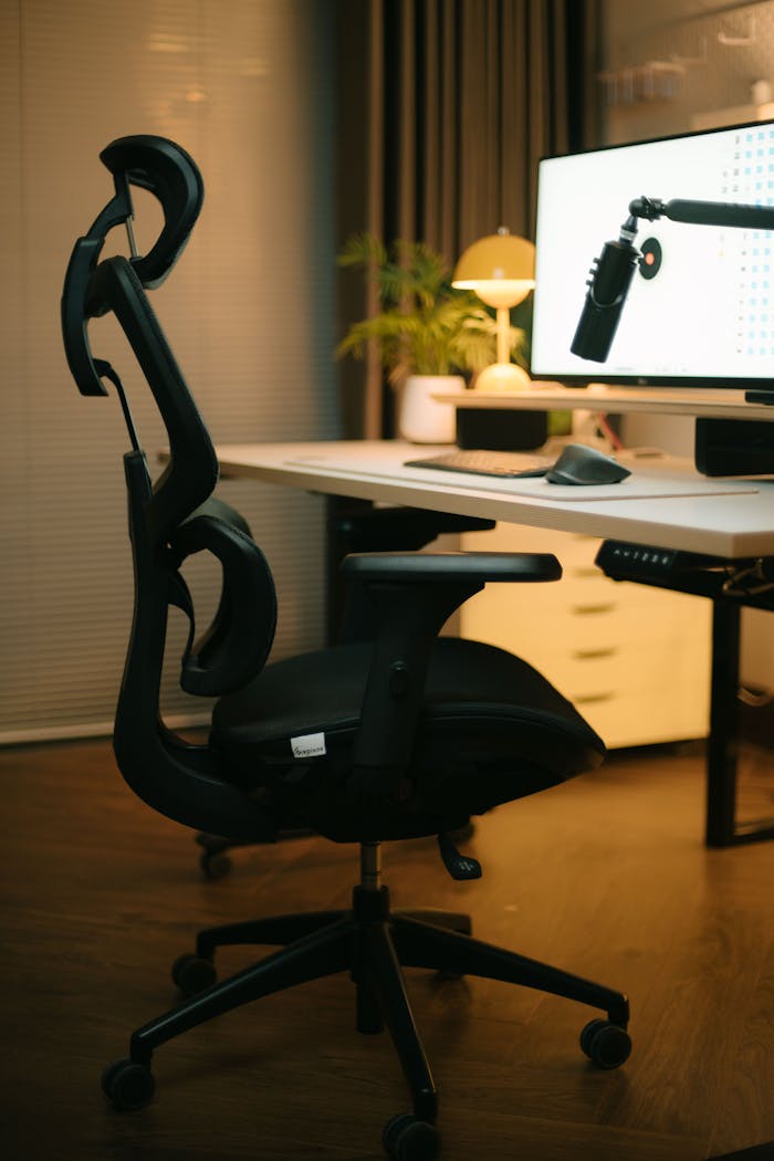 Ergonomic office chair in a cozy workspace with a desktop setup and warm lighting.