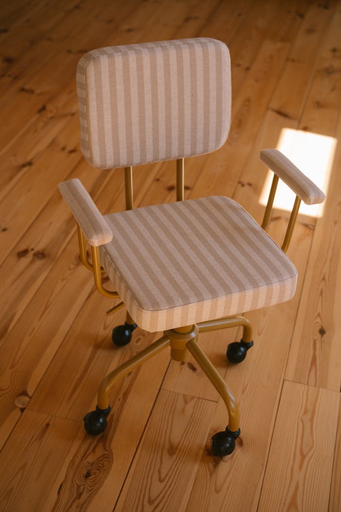 A modern striped office chair on a wooden floor warmly lit by sunlight, perfect for workspaces.