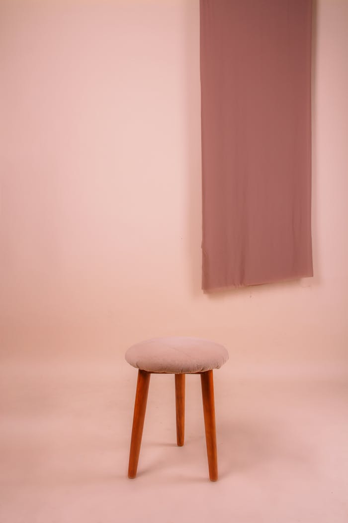 A simple wooden stool in a pastel room with soft lighting and modern decor.